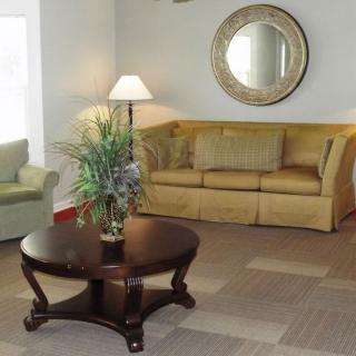 A cozy living room with a yellow sofa, dark wooden coffee table, and wall mirror.