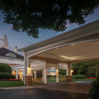 Illuminated building entrance at dusk with well-maintained landscaping.