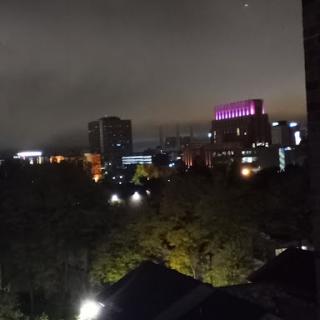A vibrant city skyline illuminated at night under a cloudy sky.