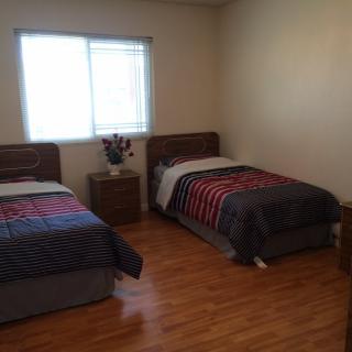 A simple bedroom with two single beds and a nightstand by the window.