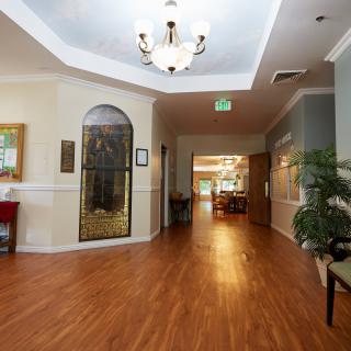 A well-lit hallway with a chandelier, hardwood floors, and decorative elements.