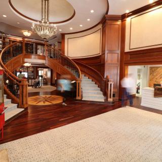 A luxurious interior featuring a grand wooden staircase and elegant chandelier.