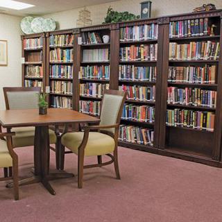 A cozy library reading area with bookshelves and a table with chairs.