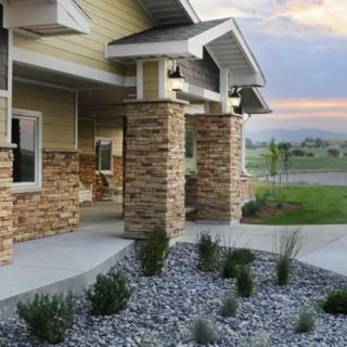 A modern house with stone columns and gravel landscaping at sunset.