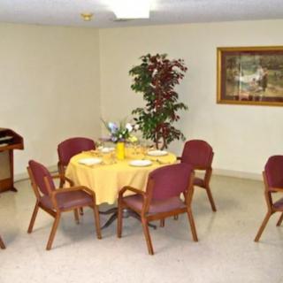 A cozy dining area with a round table set for four, featuring a decorative plant and wall art.