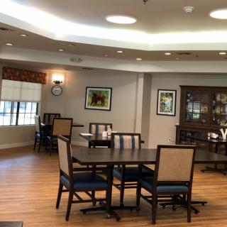 A cozy dining room with wooden tables and chairs, decorated with framed photos and a cabinet.