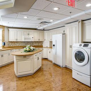 A modern kitchen with white cabinets, a center island, and a washer integrated into the space.