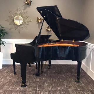 A grand piano displayed in a stylishly decorated room with a clock and plants.