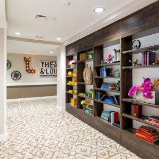 A modern hallway interior featuring a large bookshelf with various books and decorative items.