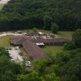 Aerial view of a rustic building surrounded by lush greenery.