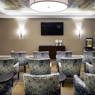 A modern conference room with patterned chairs, a television, and elegant lighting.