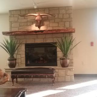 A cozy lobby featuring a stone fireplace with decorative accents and green plants.