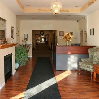 A cozy hotel lobby with a reception desk, armchair, and hallway.