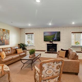 A cozy living room featuring sofas, armchairs, a coffee table, and a fireplace with a mounted television.