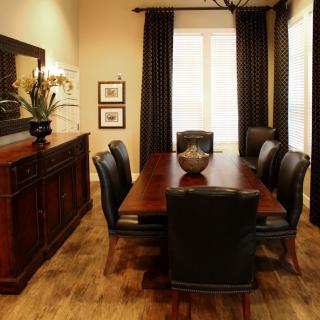 A stylish dining room with a wooden table surrounded by chairs, adorned with elegant decor and curtains.