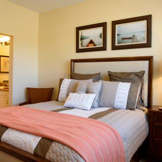 A cozy bedroom with a neatly made bed, adorned with decorative pillows and a warm blanket.