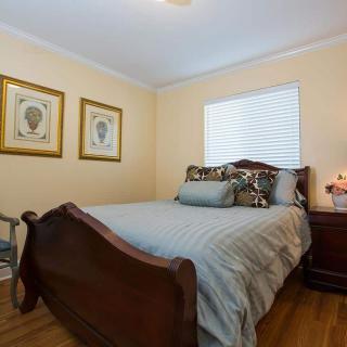 A cozy bedroom with a wooden bed, decorative pillows, and wall art.