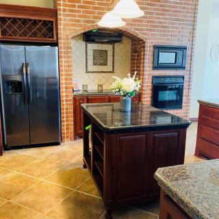 Modern kitchen with a central island, brick accents, and stainless steel appliances.