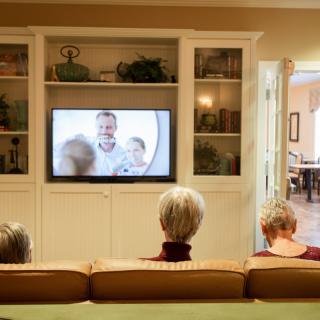 Three people sitting on a couch watching television in a cozy living room.