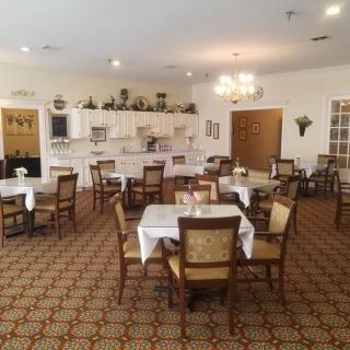 A spacious dining room with neatly arranged tables and chairs, featuring elegant decor and a warm, inviting atmosphere.