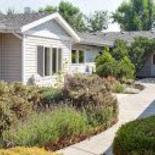 A quaint house with well-maintained landscaping and a variety of plants lining the pathway.