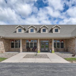 A spacious stone-front house with a gabled roof and large windows under a partly cloudy sky.