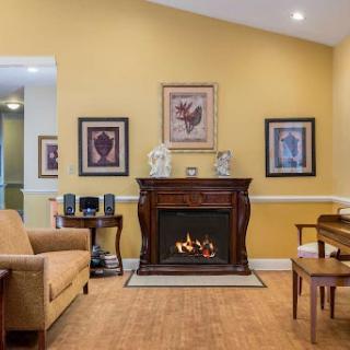 A cozy living room featuring a decorative fireplace, comfortable furniture, and framed artwork on the walls.