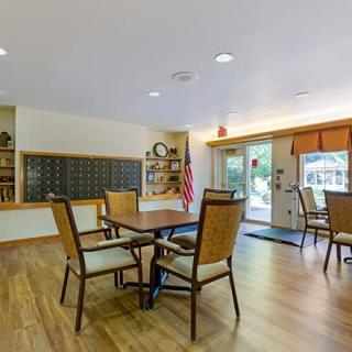 A well-lit lobby area featuring tables and chairs on a wooden floor.