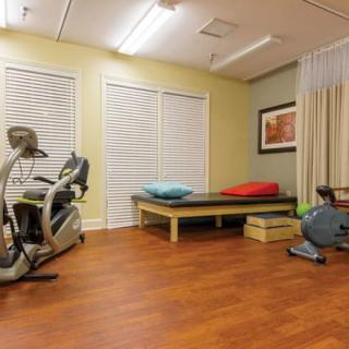 A well-equipped exercise and therapy room with fitness machines and a comfortable resting area.
