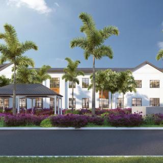 A modern residential building surrounded by palm trees and a landscaped garden.