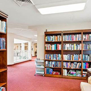 A cozy library with wooden bookshelves filled with books and a well-lit reading area.