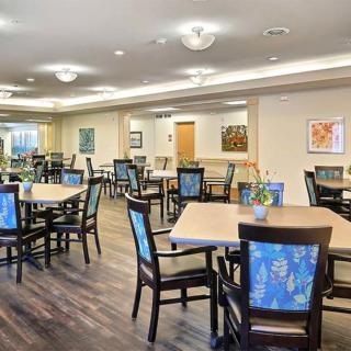 A spacious dining area with neatly arranged tables and chairs, featuring elegant lighting and wooden flooring.