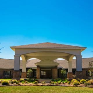 An inviting building entrance with a landscaped front yard under a clear blue sky.