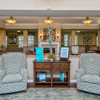 A comfortable lobby seating area with two patterned armchairs and a wooden table, adorned with decor and soft lighting.