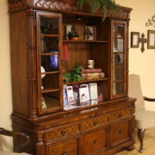 A classic wooden cabinet with glass doors and shelves, decorated with books and plants.
