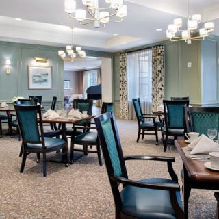 A well-lit dining room with neatly arranged tables and chairs, featuring elegant decor and ample natural light.