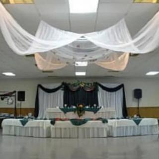 An elegantly decorated event space with draped ceilings and a prepared stage area.
