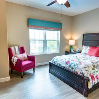 A cozy bedroom with a vibrant chair and floral bedding.