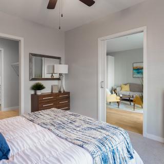 A modern and cozy bedroom with a stylish dresser, mirror, and open view to an adjoining room.