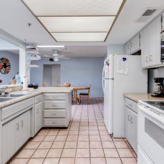A spacious kitchen with white cabinets, countertops, and a tiled floor.