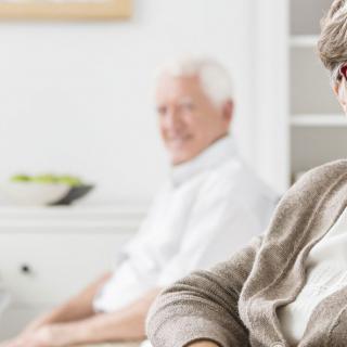 Two older adults relaxing in a bright living room setting.