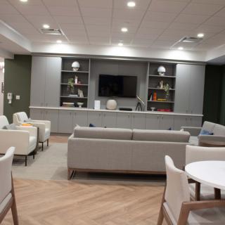 A modern lounge area featuring comfortable seating, bookshelves, and a television.