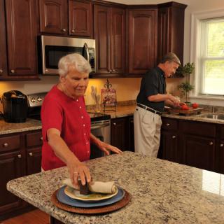 An elderly couple preparing food together in a cozy kitchen setting.