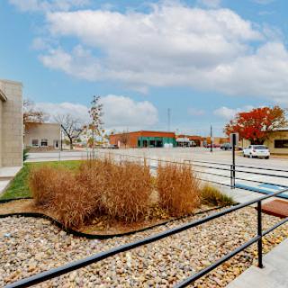 A serene urban landscape with a well-maintained garden, buildings, and a cloudy sky.