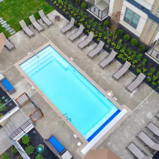 Aerial view of a residential swimming pool with surrounding lounge chairs and landscaped areas.