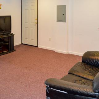 A simple living room with a television, a couch, and a carpeted floor.