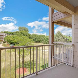 A balcony with a view of trees under a clear blue sky.