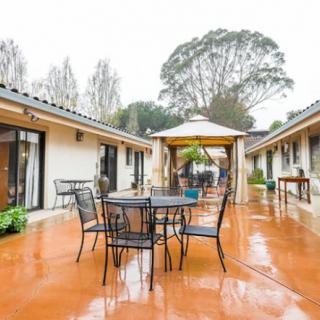 A cozy outdoor courtyard with tables and chairs, featuring a central gazebo on a rainy day.