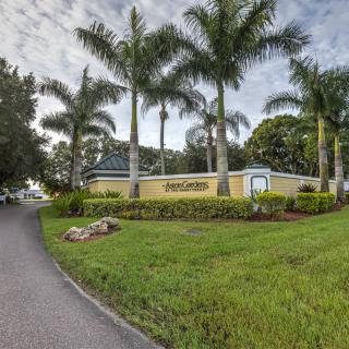 A landscaped entrance with palm trees and a building in a tropical setting.