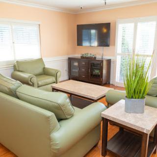 A cozy living room featuring green sofas, a coffee table, and a TV against a light-colored wall.